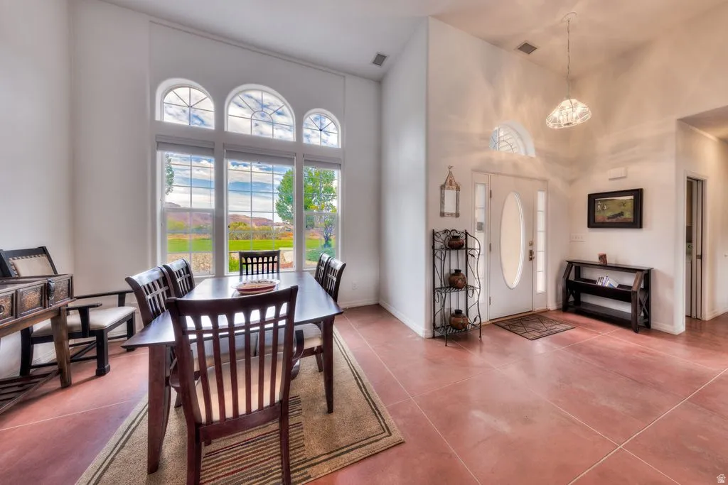 Entryway with a white double-pane front door, red tile flooring, and vaulted ceilings