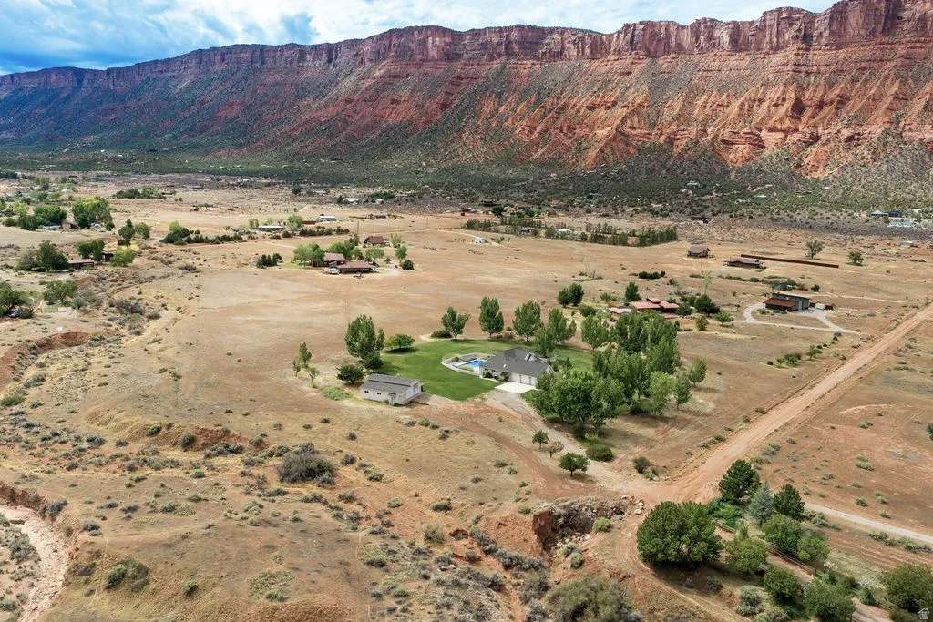 Expansive property featuring a private swimming pool, surrounding green lawn, multiple mature trees, and a distant mountain backdrop