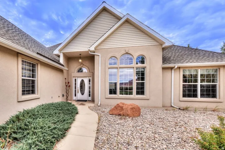 Stucco exterior with gabled roofline, arched entry, decorative front door with oval glass insert, and large arched windows