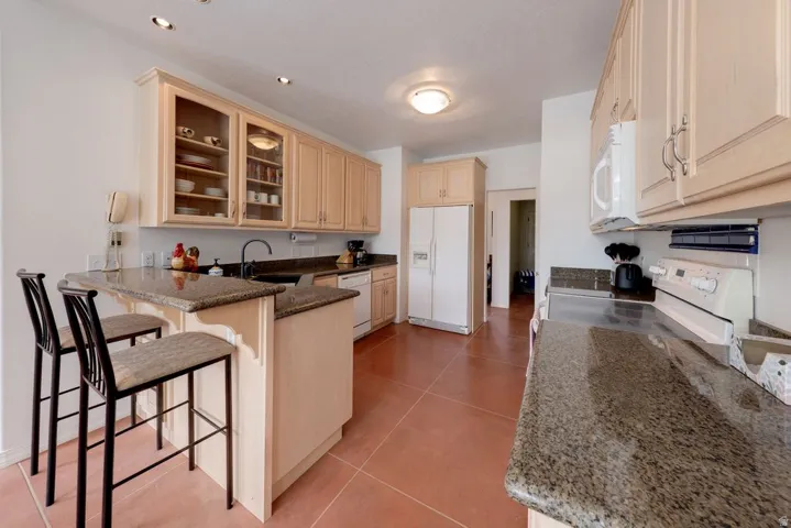 Kitchen featuring wood-finish cabinetry, granite countertops, recessed lighting, and a breakfast bar
