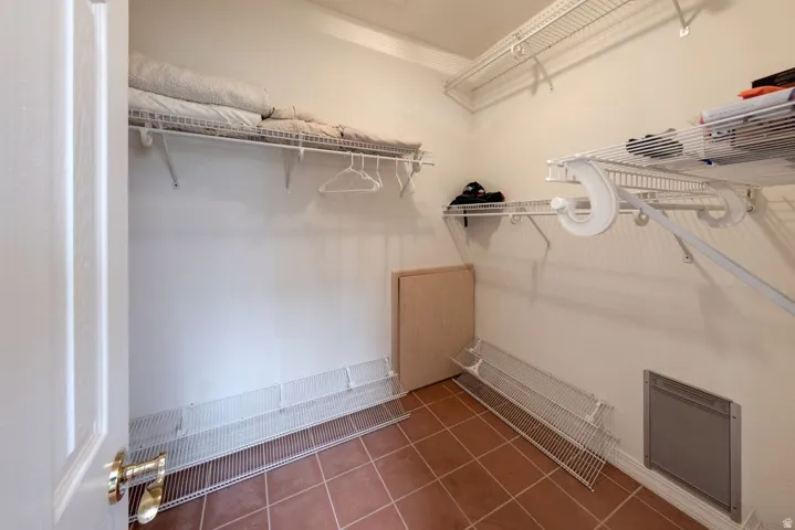 White wire shelving system, terracotta-style floor tiles, and a white paneled door with brass hardware