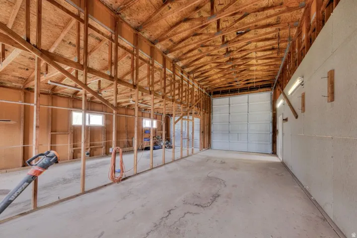 Spacious interior with exposed wood framing, concrete flooring, and a large roll-up door