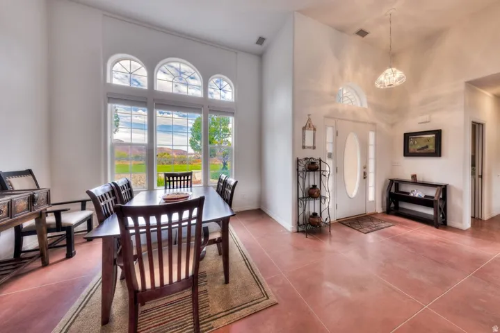 Entryway with a white double-pane front door, red tile flooring, and vaulted ceilings