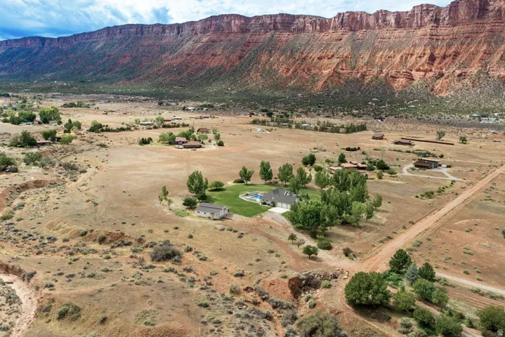 Expansive property featuring a private swimming pool, surrounding green lawn, multiple mature trees, and a distant mountain backdrop