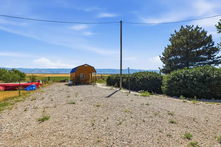 Gravel lot with a detached shed featuring a blue gambrel roof