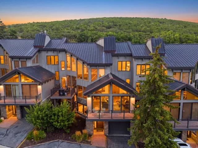 Multi-level exterior with metal roofing, multiple balconies, and stone accents