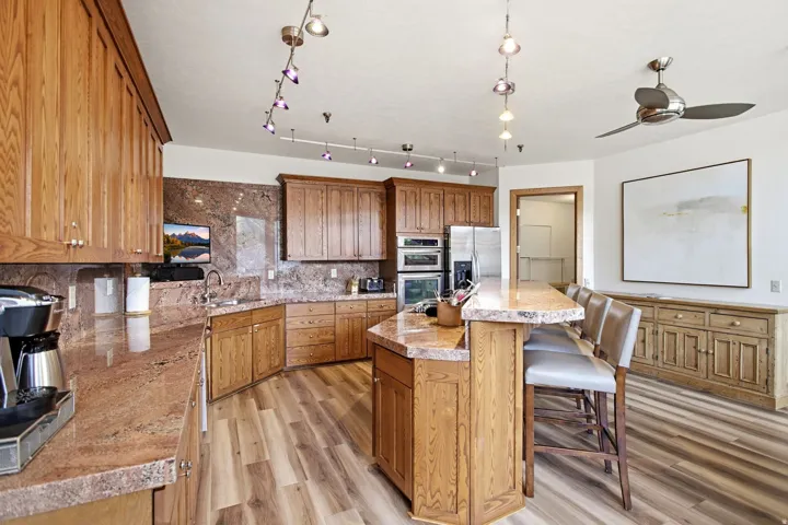 Kitchen featuring wood cabinetry, coordinating countertops, an integrated eat-at island, and wood-finish flooring