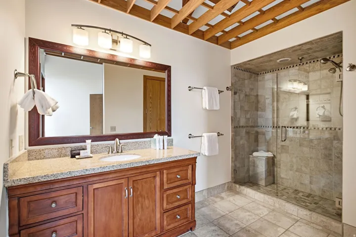 Wood vanity with a stone countertop, an undermount sink, and a framed mirror