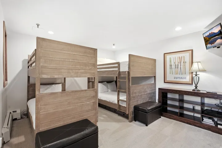 Room featuring two built-in bunk bed structures with wood-finish frames, recessed lighting, and a wall-mounted display