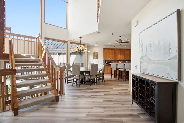 Two-story windows, vaulted ceiling, wood-finish flooring, wood staircase with carpet runner, and recessed lighting