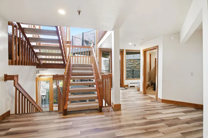 Wood-finish flooring throughout, carpeted stairs, and wood railings