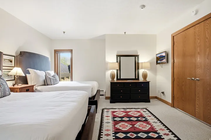 Carpeted flooring, a window with wood trim, and a wood-finish door with brushed nickel hardware