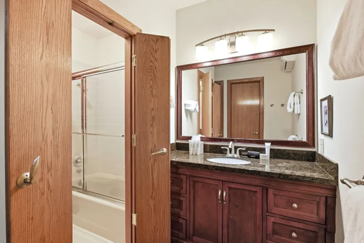 Dark wood-finish vanity with a stone countertop, an integrated sink, and a framed mirror