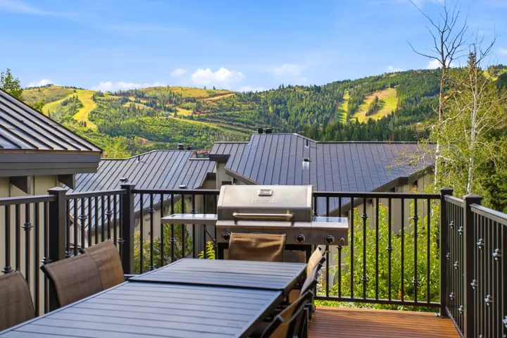 Wood-finish deck with black iron railings, a built-in grill, and expansive mountainous terrain