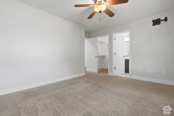 Neutral wall color, ceiling fan with integrated lighting, soft carpet flooring, built-in shelving in closet