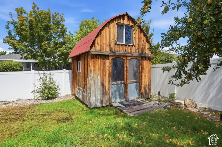 Wood-sided outbuilding with red metal roof, upper-level window, and ground-level doors