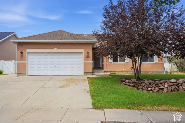 Stucco exterior with a two-car garage, concrete driveway, and front lawn