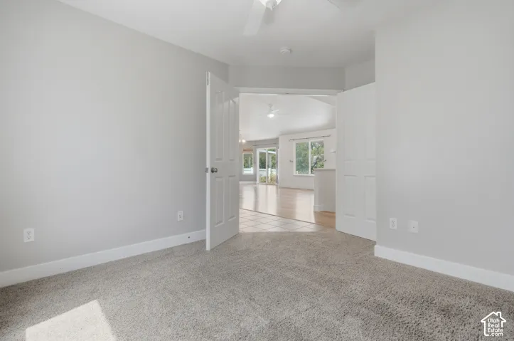 Neutral gray wall color, light gray carpeting, white double doors, and a ceiling fan