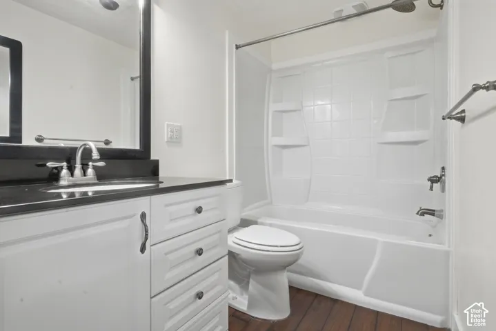 White vanity with dark hardware, dark countertop, and integrated sink