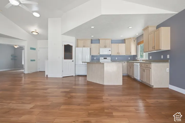 Open-concept living area featuring wood-finish flooring, vaulted ceilings, and recessed lighting
