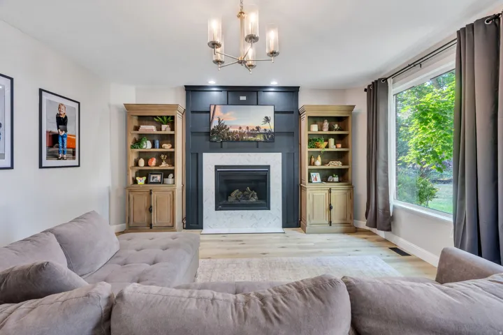 Fireplace with a patterned tile surround, custom built-in cabinetry, and integrated lighting