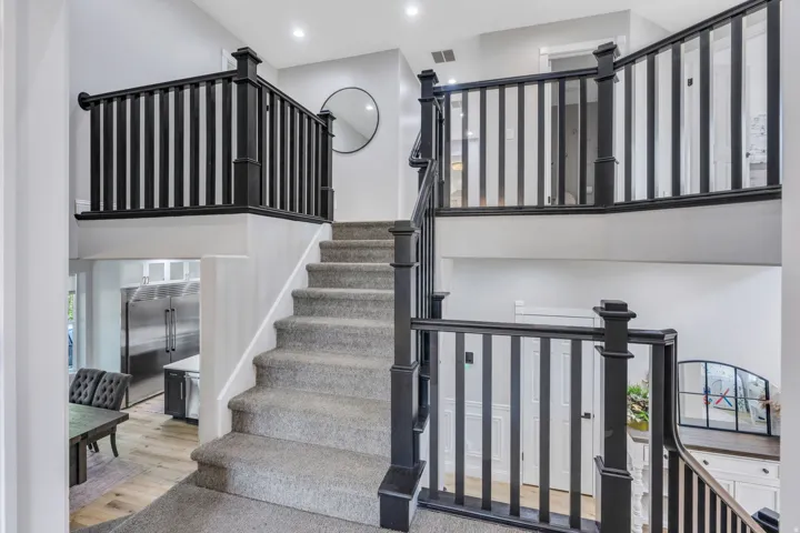 Carpeted staircase with dark wood newel posts and railings, recessed lighting, and light gray wall finishes