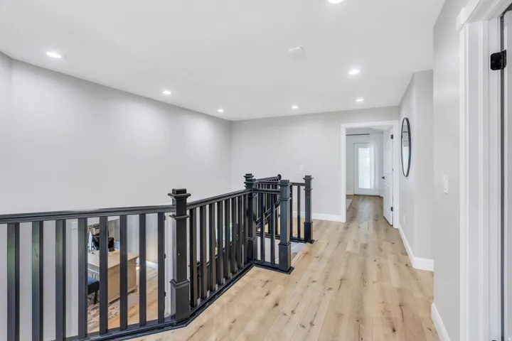 Wood-finish flooring, recessed lighting, and a black baluster railing