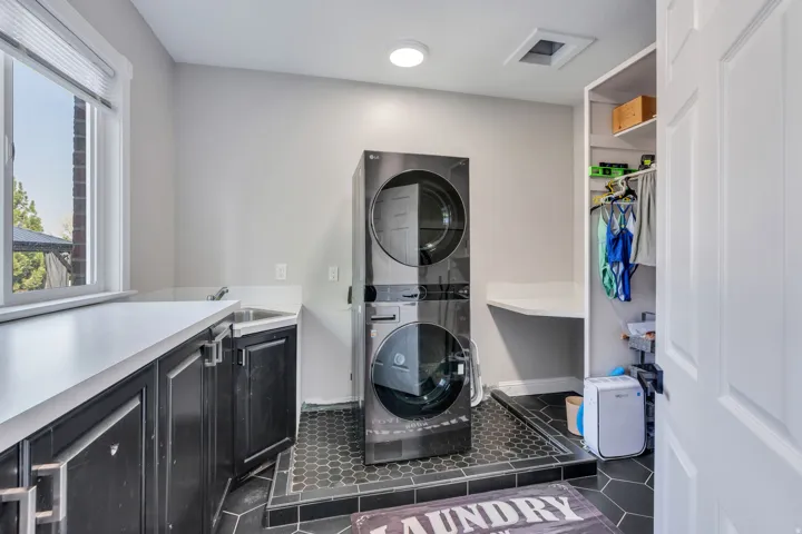 Laundry area with dark wood-finish cabinetry, light-toned countertops, a utility sink, and a built-in storage closet