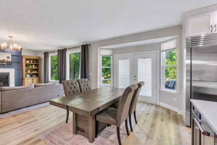 Open-concept living space with light wood-finish flooring, a white mantel fireplace, and a built-in bookshelf