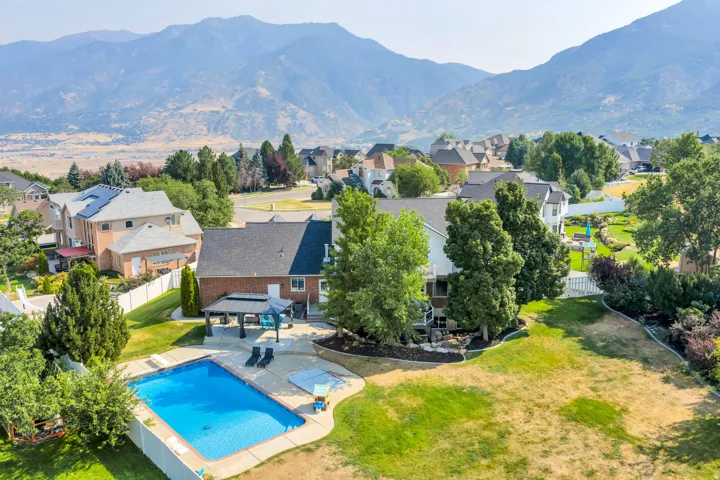 Expansive backyard featuring a rectangular swimming pool, concrete pool deck, and a covered patio structure