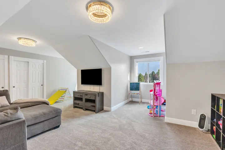 Spacious room with sloped ceilings, recessed lighting, and a large window