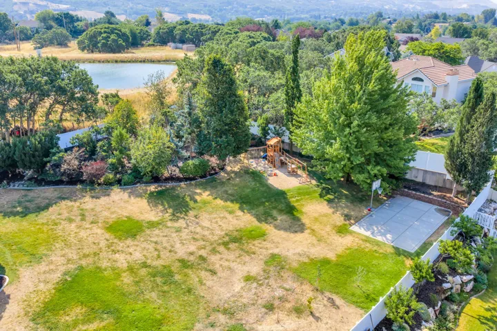 Expansive backyard featuring a manicured lawn, established landscaping, and a fenced perimeter