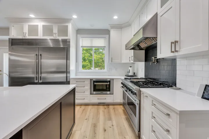 Kitchen featuring white cabinetry, stainless steel appliances, light wood-finish flooring, white countertops, and a white subway tile backsplash