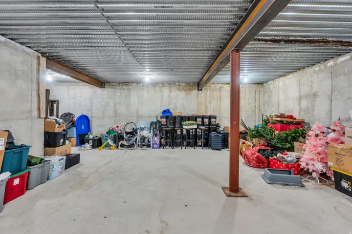 Concrete foundation walls, exposed steel beams, corrugated metal ceiling, and concrete floor