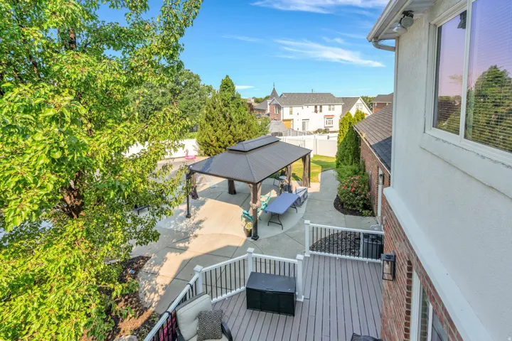 Multi-level outdoor space featuring a composite deck with white railings, a paved patio, and a covered gazebo