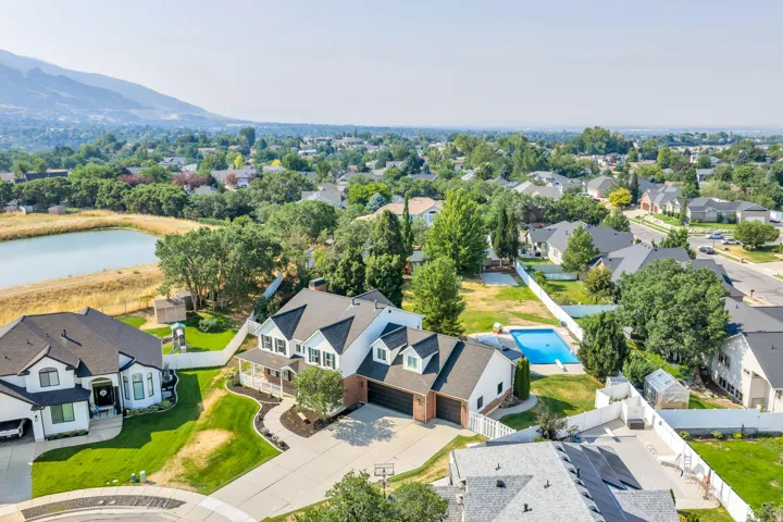 Two-story residence featuring a covered front porch, attached garage, and a fenced backyard with an in-ground pool