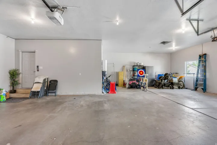 Spacious garage featuring a concrete floor, overhead garage door opener, multiple recessed lighting fixtures, and an interior access door
