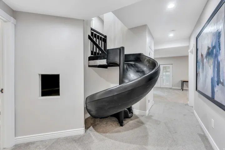 Built-in spiral slide, carpeted flooring, recessed lighting, white trim, and a white paneled door