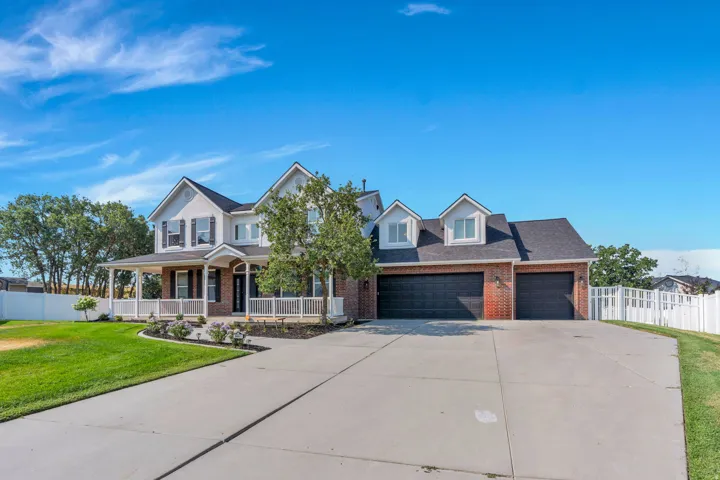 Stately exterior featuring brick and siding, a covered front porch, a two-car garage, and a concrete driveway