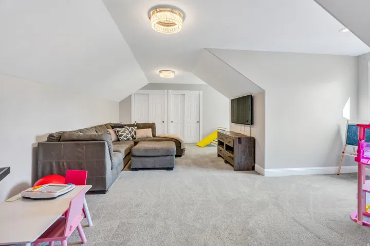 Carpeted room with sloped ceilings, recessed lighting, and two panel closet doors