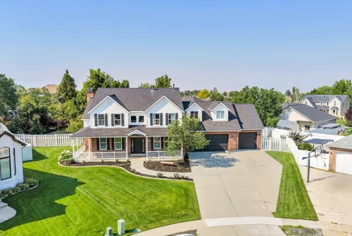 Two-story residence featuring white siding, brick accents, a covered front porch, and an attached two-car garage