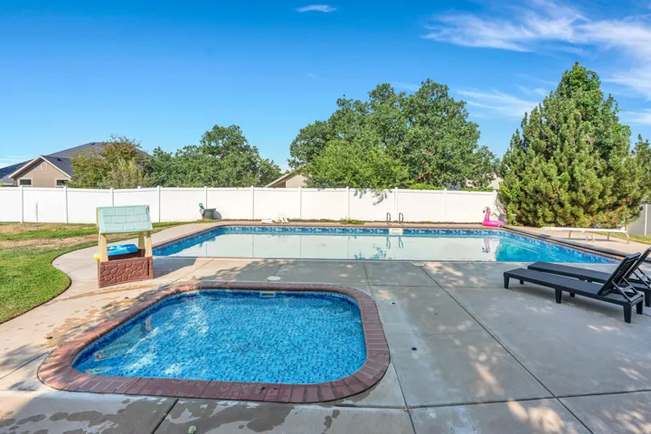 Expansive concrete patio featuring an in-ground swimming pool and an integrated spa