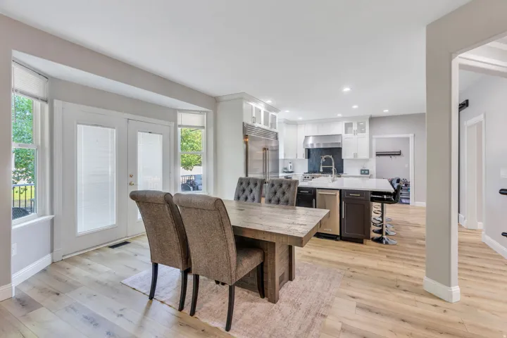 Light wood-finish flooring throughout, stainless steel appliances, recessed lighting, white kitchen cabinetry, and a kitchen island with seating