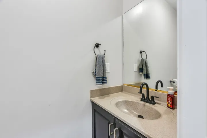 Built-in vanity with a speckled countertop, integrated sink, and matte black faucet