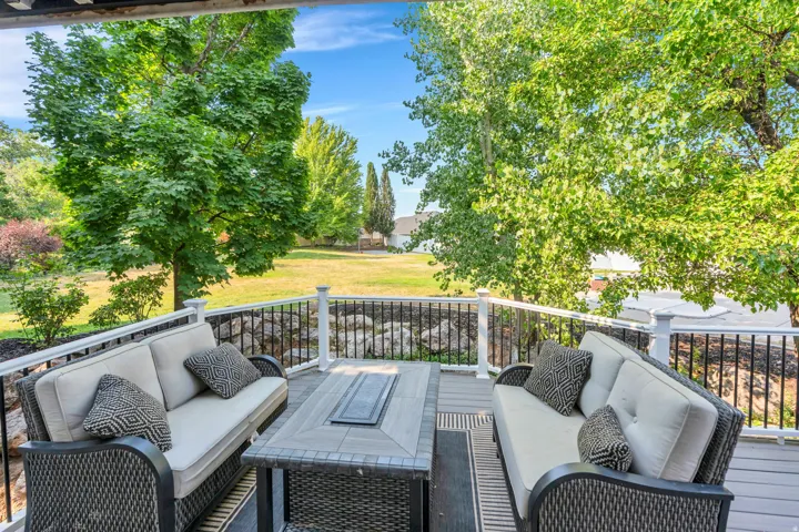 Expansive outdoor deck with gray wood-finish flooring, white balusters, and black metal railings