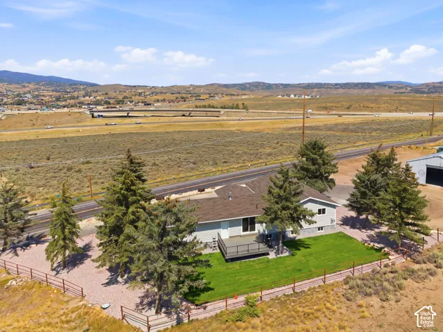 Ranch-style residence featuring a rear deck, manicured lawn, and mature trees
