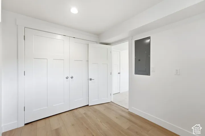 Wood-finish flooring with white baseboards, white walls, and a recessed ceiling light