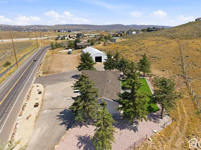 Gabled roofline, adjacent paved road, established trees, expansive gravel drive, and a detached outbuilding