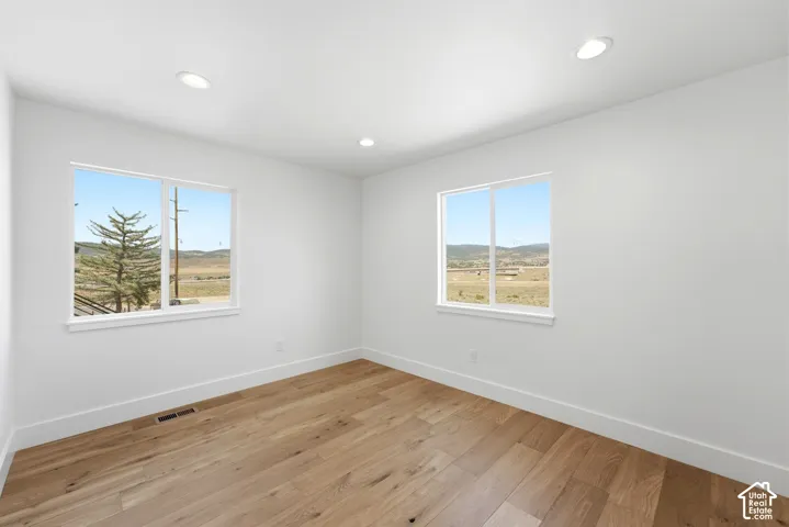 Recessed lighting, wood-finish flooring, white walls, and two windows with white trim