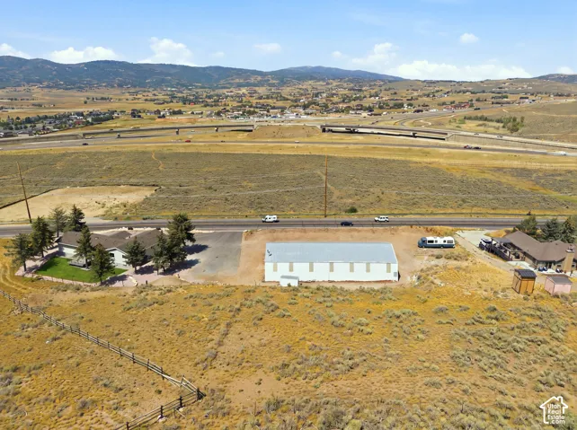 Expansive property featuring a single-story residence with a gabled roof, an additional large detached structure, and a fenced perimeter
